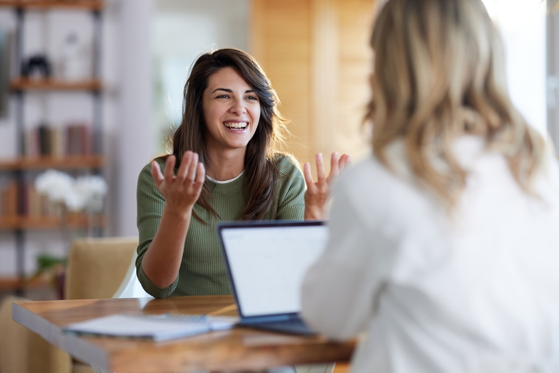Zwei Frauen unterhalten sich Frau mit Laptop unterhält sich mit einer anderen Frau