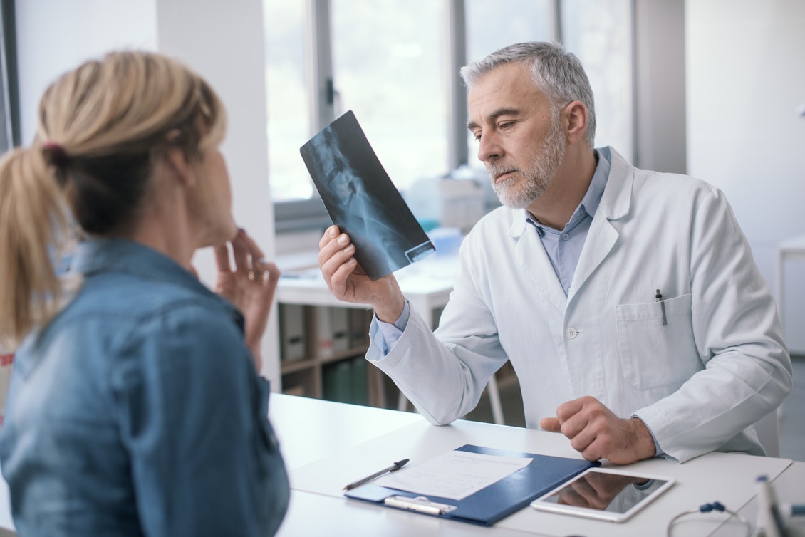 Arzt erläutert eine Röntgenaufnahme Arzt schaut sich vor Patientin Röntgenaufnahme an