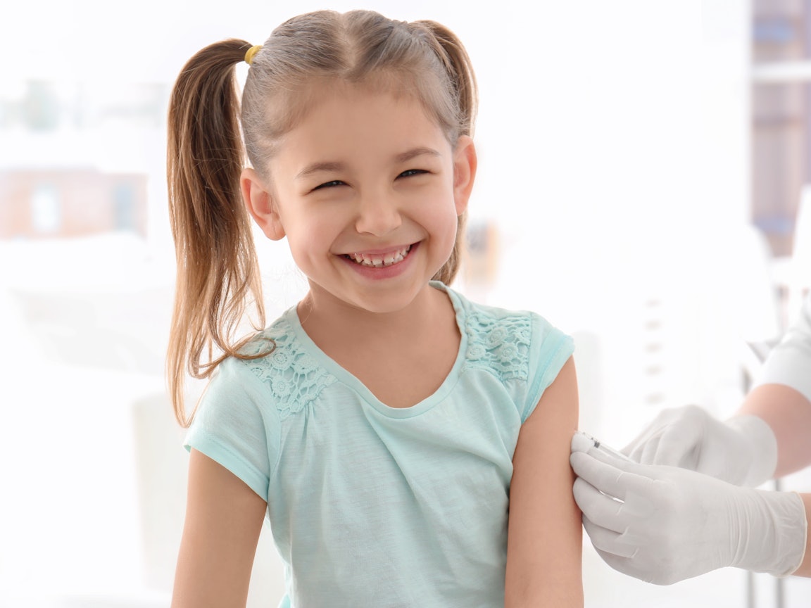 Junges Mädchen bei Impfung Jugnes Mädchen lacht in die Kamera und wird von Arzt geimpft