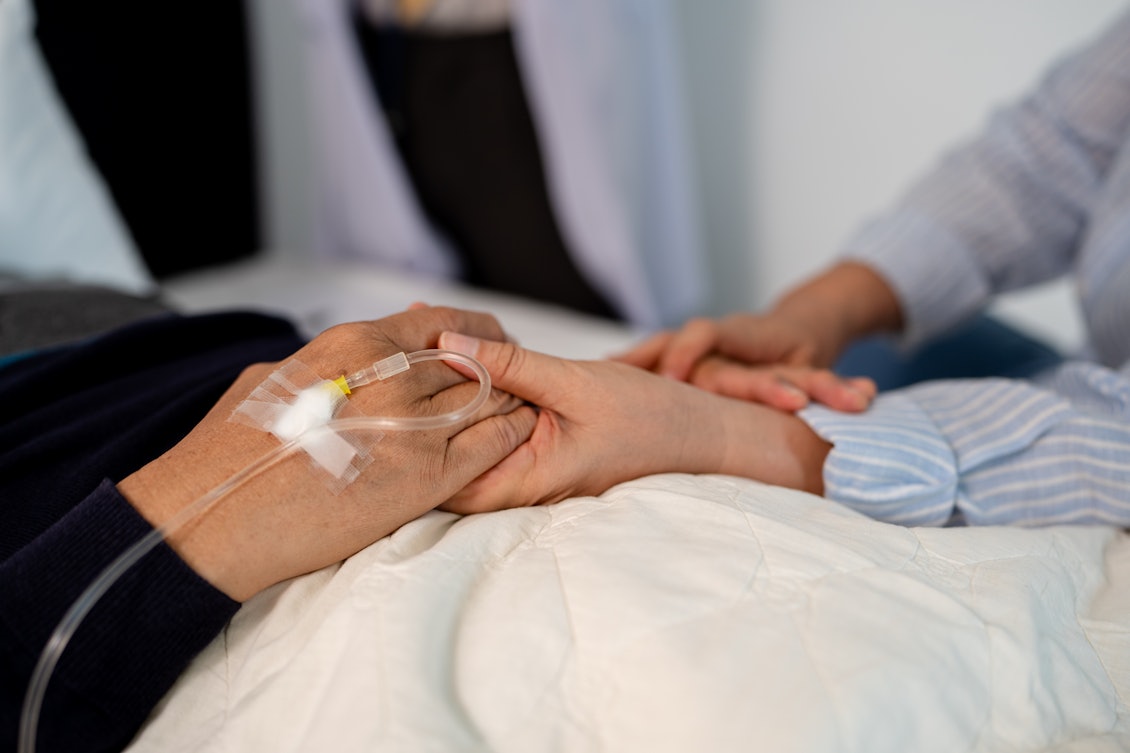 Frau hält die Hand eines Patienten Frau hält die Hand eines Patienten, der eine Infusion erhält