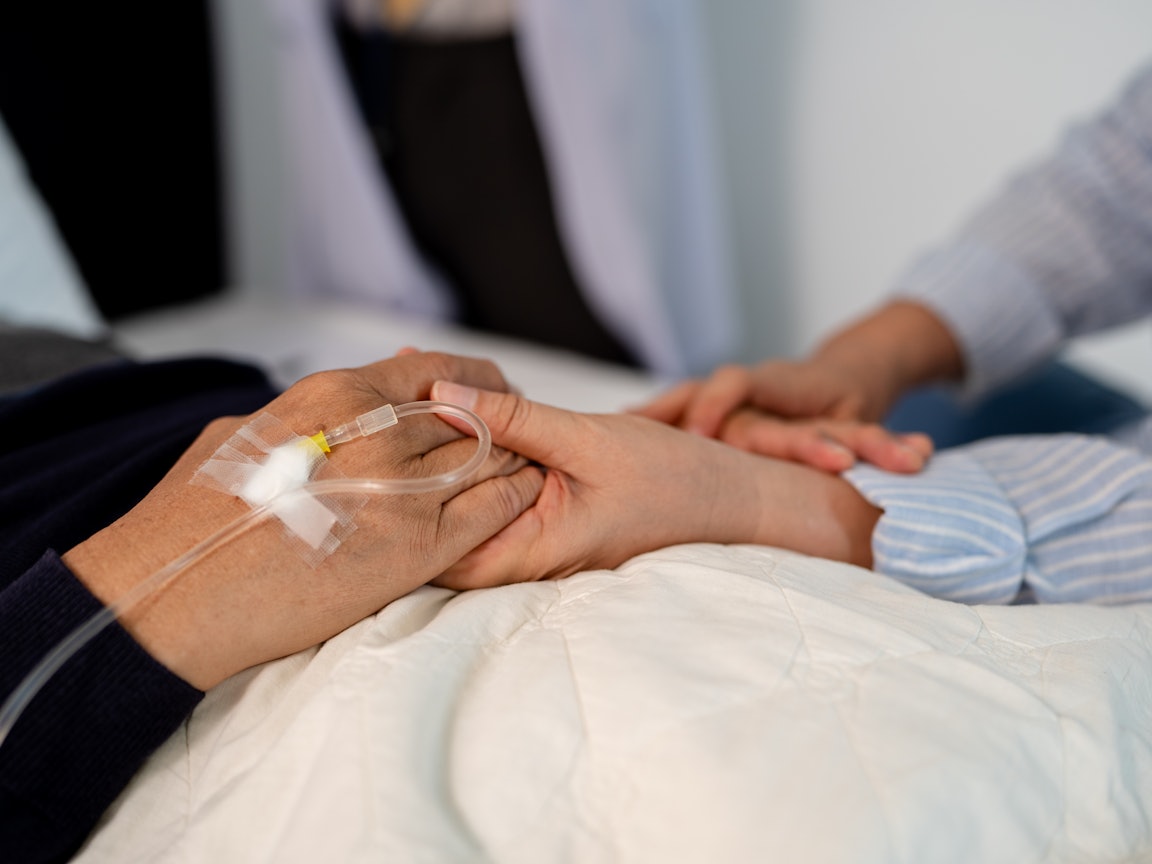 Frau hält die Hand eines Patienten Frau hält die Hand eines Patienten, der eine Infusion erhält