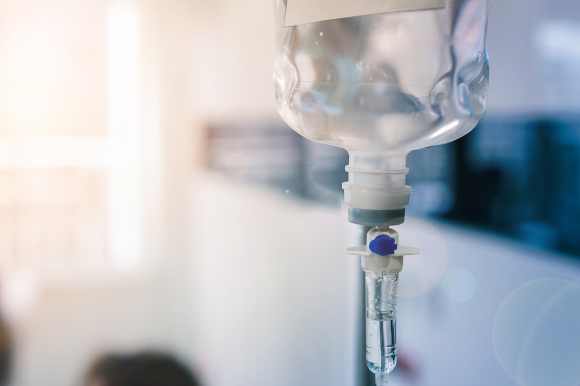 Infusionsflasche mit Tropf in Nahaufnahme Im Vordergrund sieht man eine Infusionsflasche mit Tropf