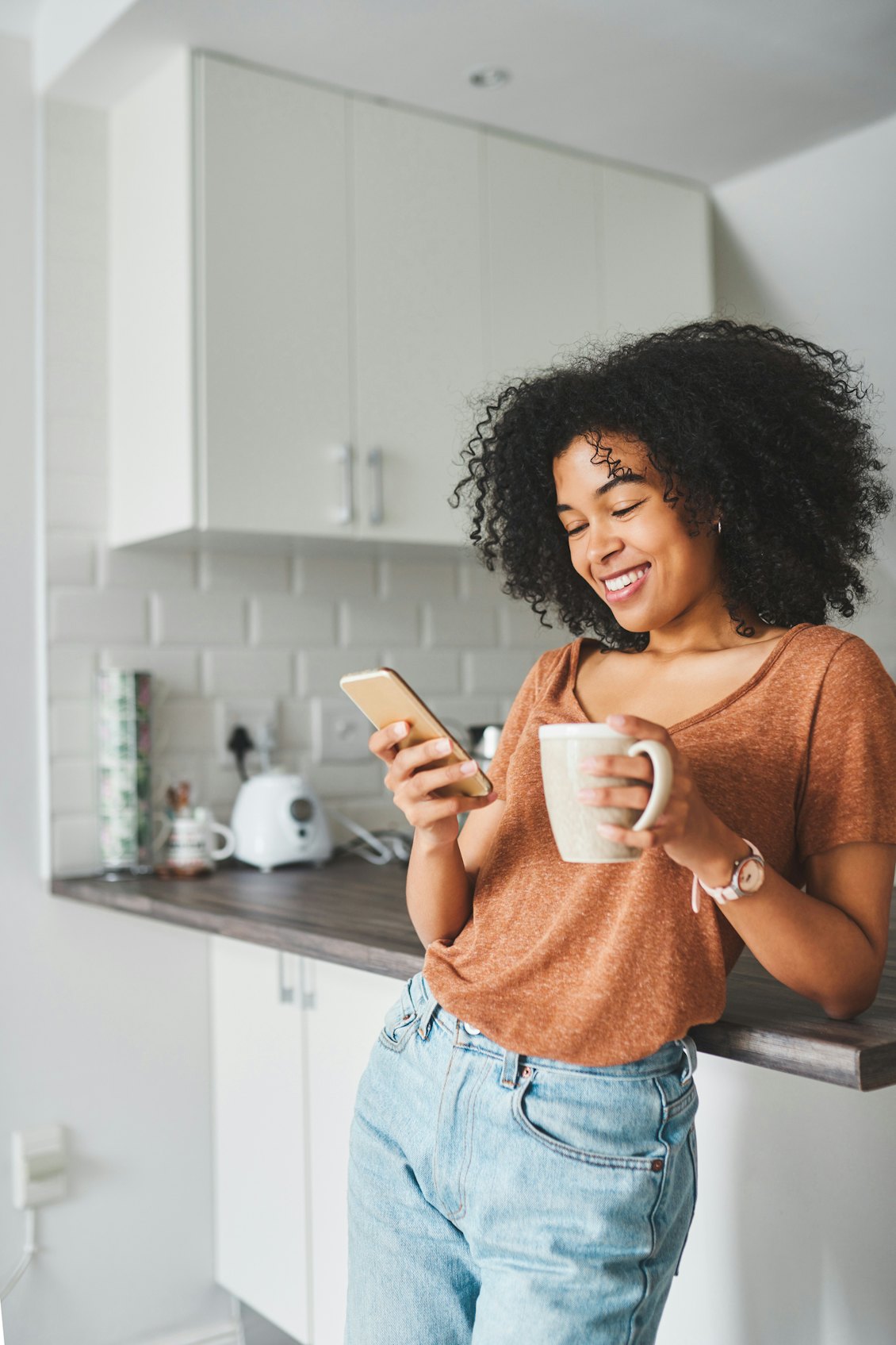 Frau mit Handy und Kaffee in der Hand Frau trinkt Kaffee und ist dabei am Handy