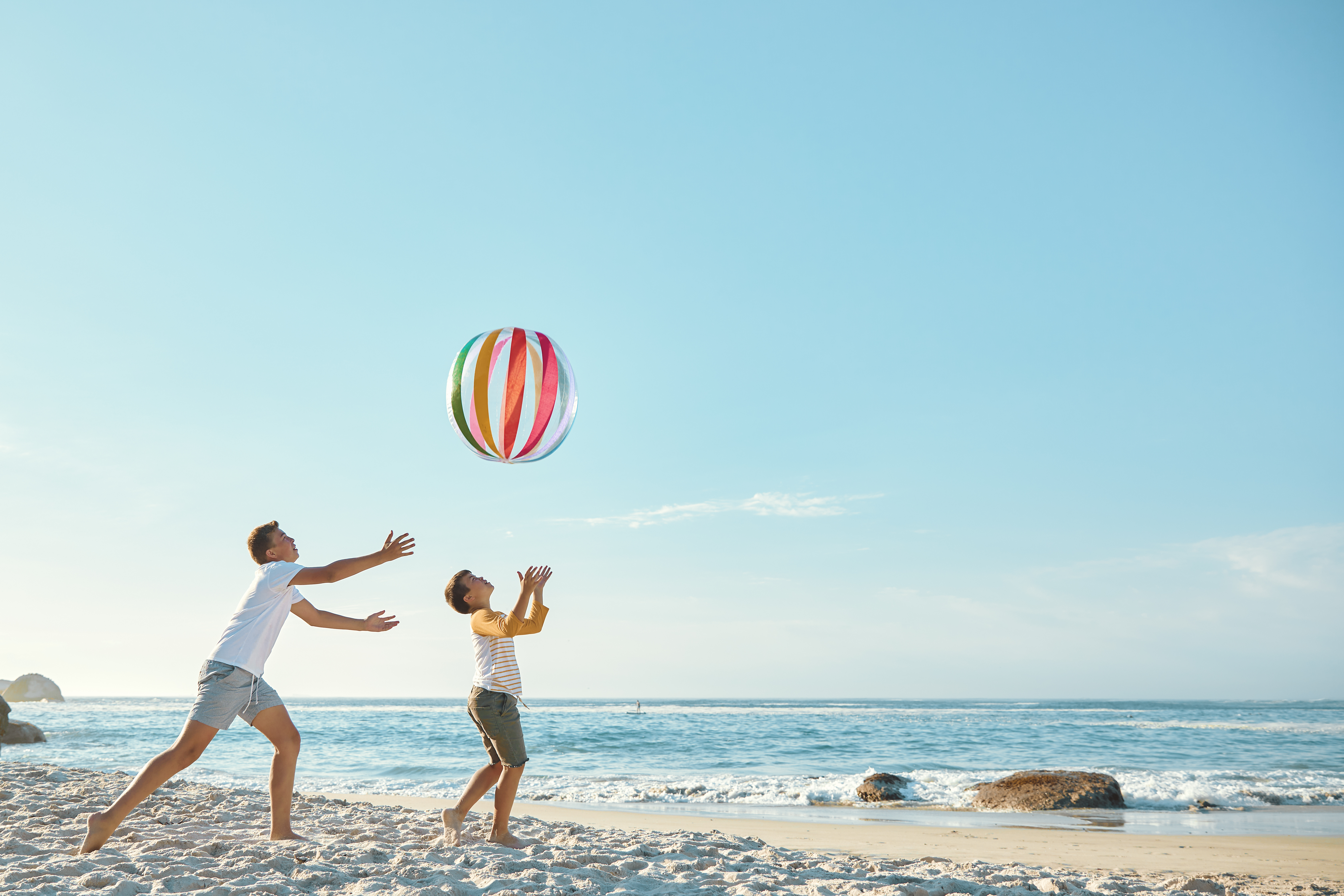 Zwei Jugendliche genießen ein Ballspiel am Meer