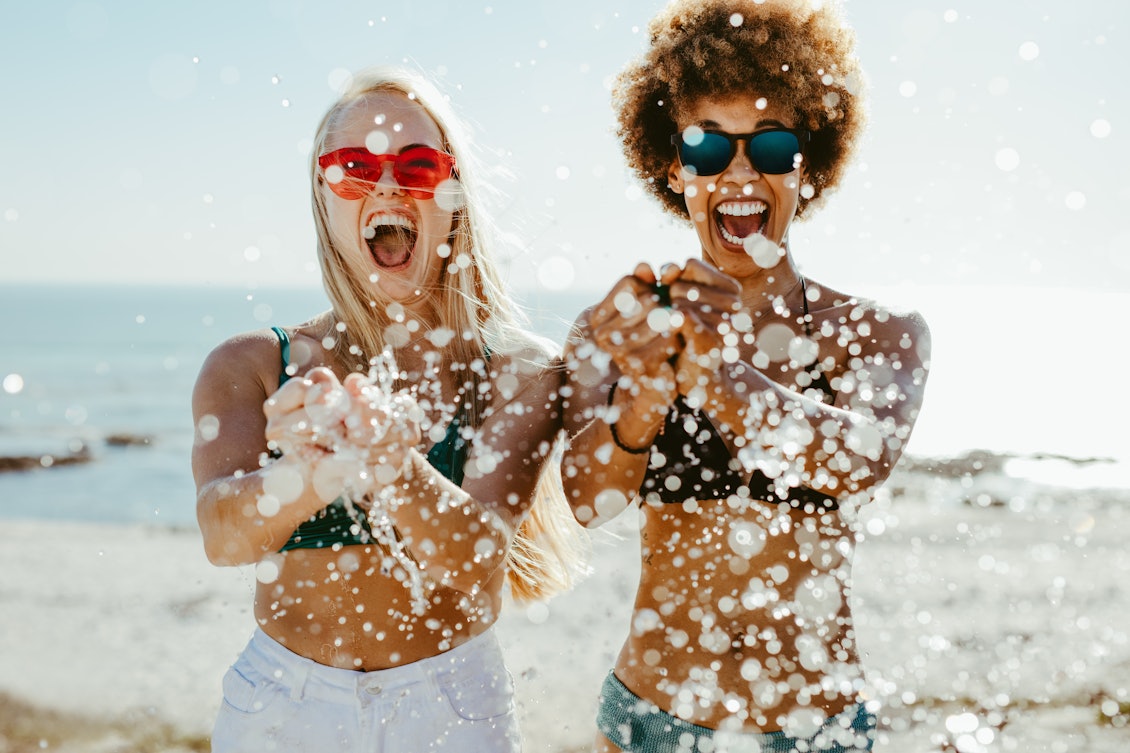 Frauen am Strand Zwei Frauen am Strand spritzen mit Wasser