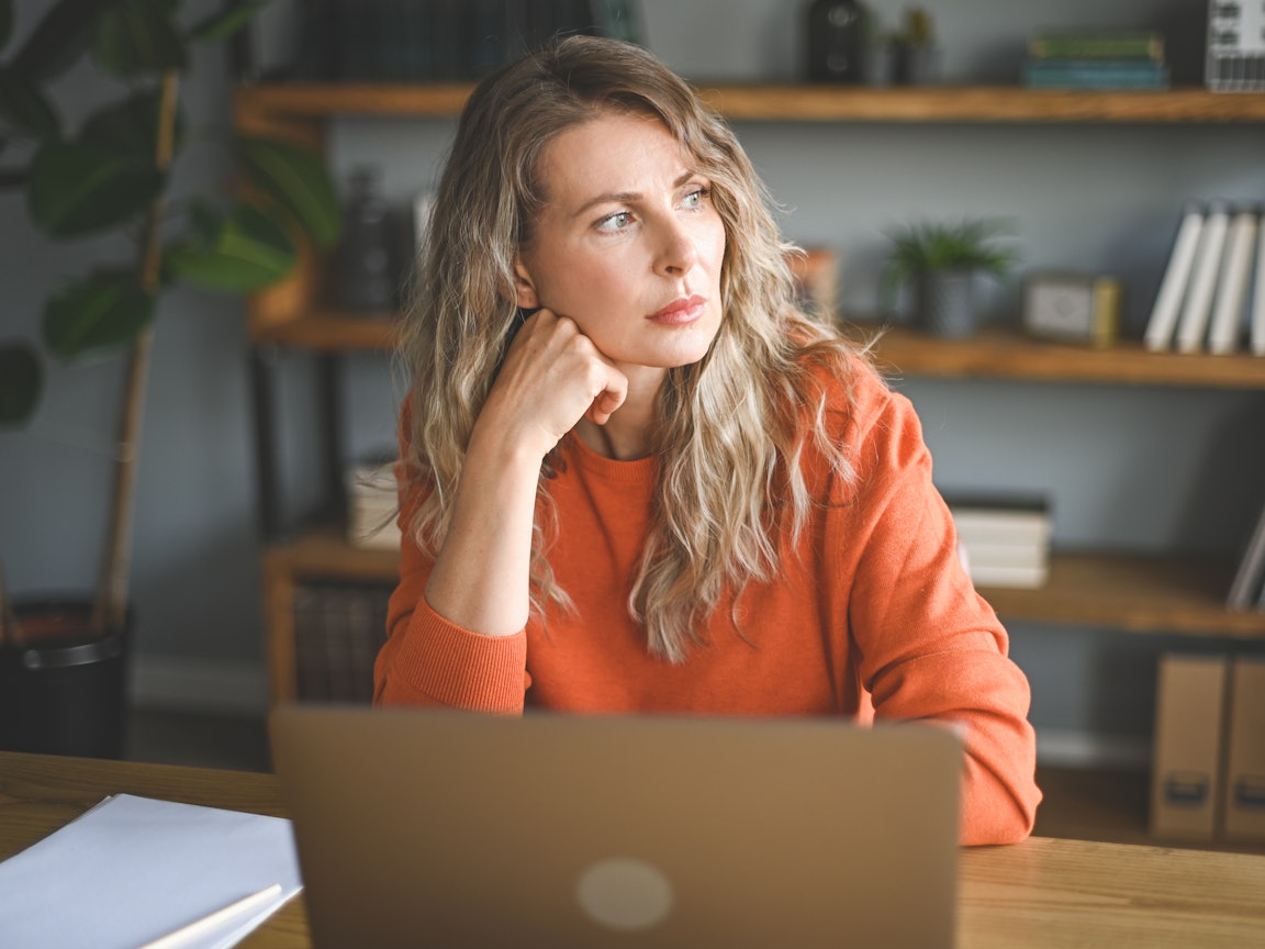 Nachdenkliche Frau mittleren Alters sitzt am Laptop Frau sitzt vor dem Laptop