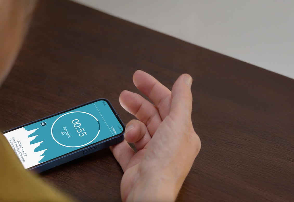Preventicus Messung per App Person hält Hand auf Handykamera, um Preventicus-Messung durchzuführen