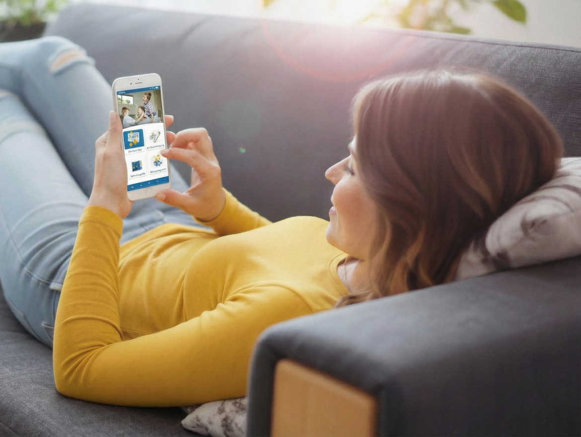 Frau mit Smartphone auf dem Sofa bei Nutzung der BKK Linde Service App