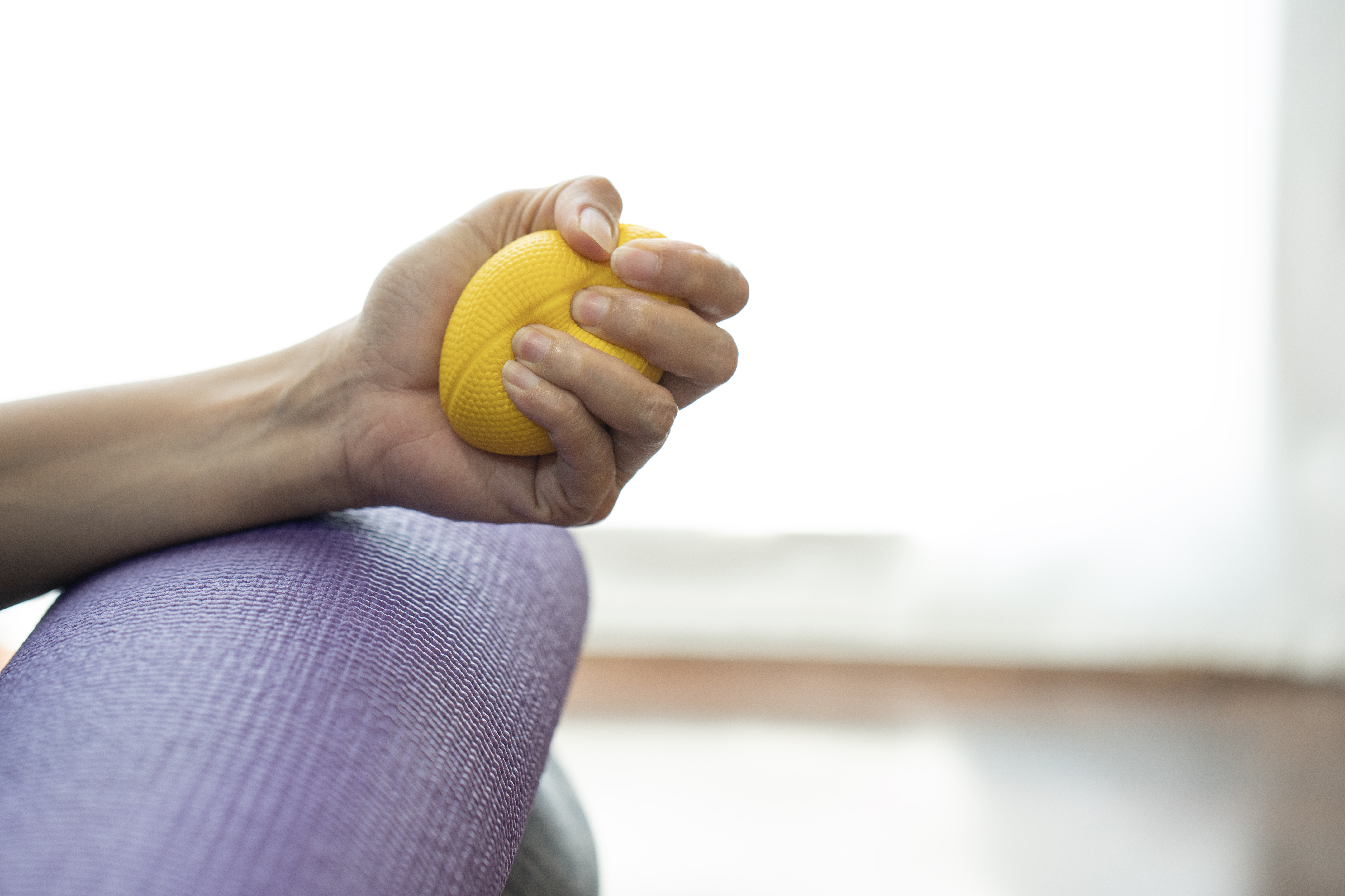 Frau mit gelbem Antistressball in der Hand