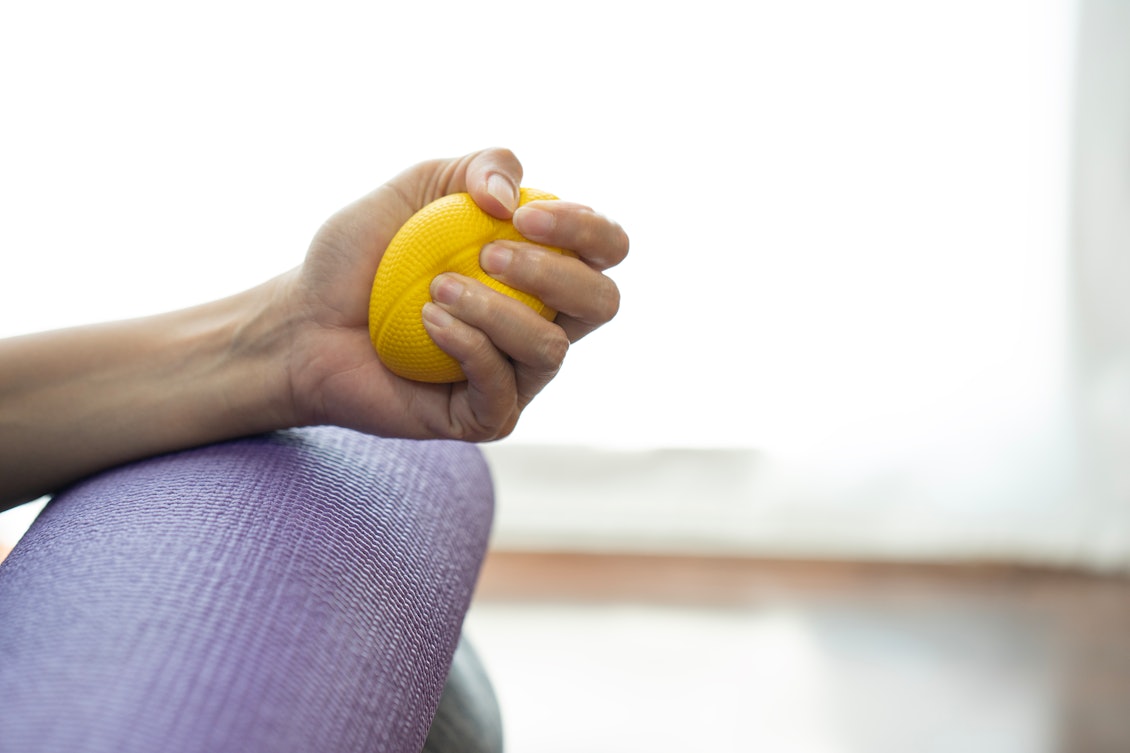 Frau hat einen gelben Antistressball in der Hand Frau mit gelbem Antistressball in der Hand