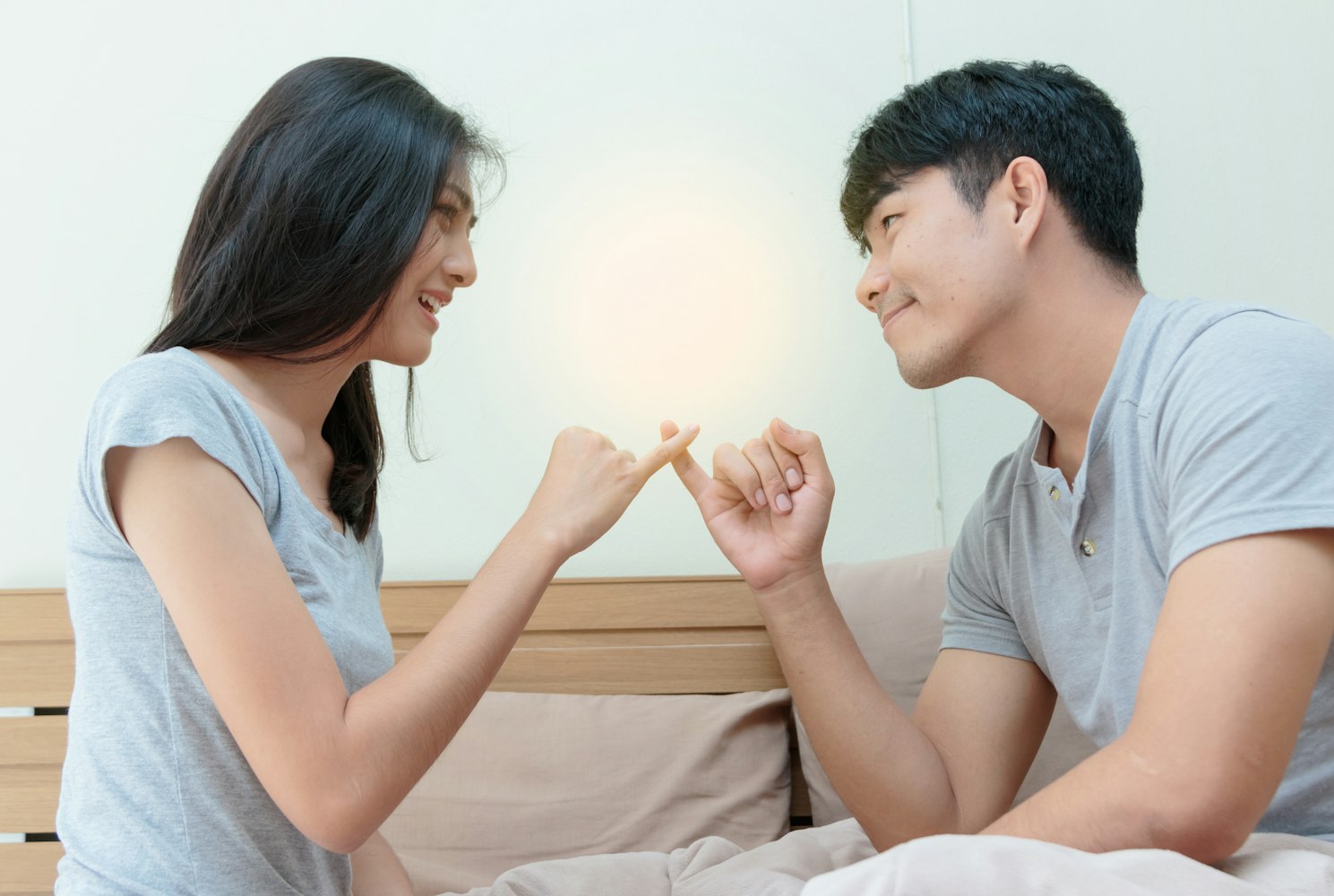 Couple reconciling after an argument, making a pinky promise.