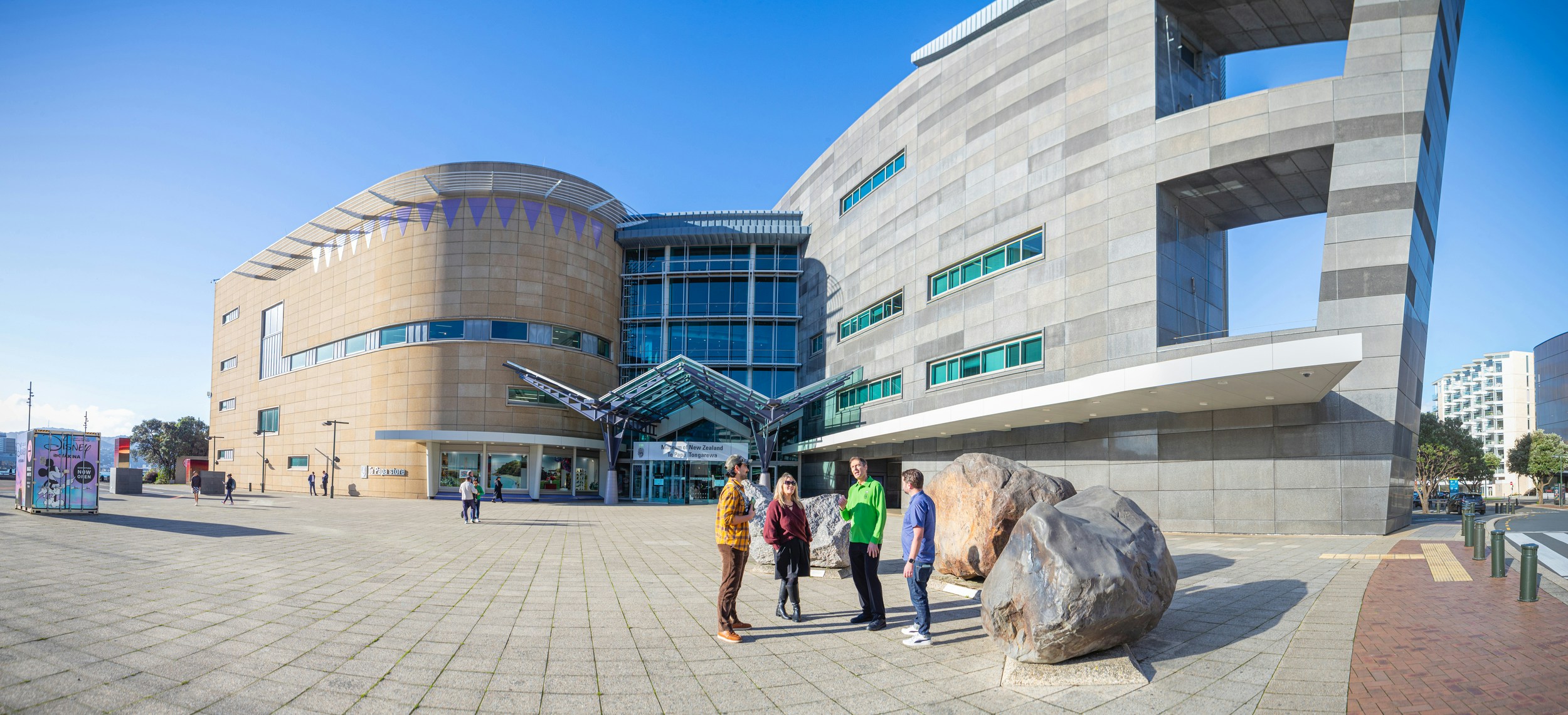 A Te Papa Host talks with visitors in front of Te Papa.