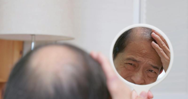 man looking at his hair in a mirror