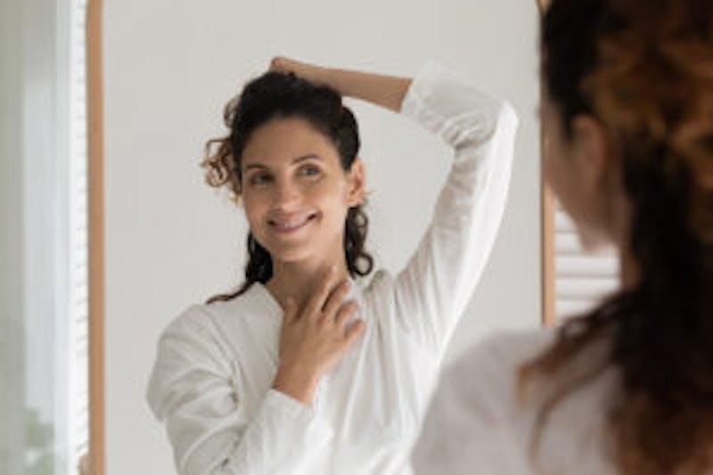 woman in a white long sleeve top touching her hair