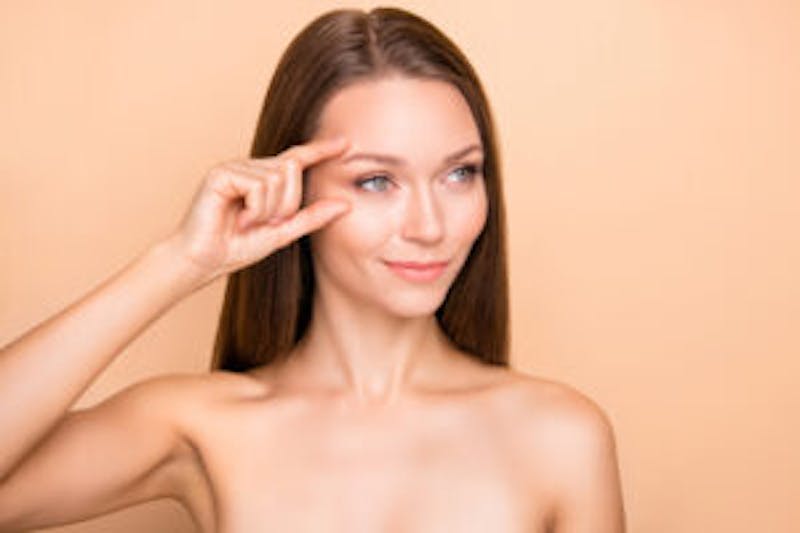 woman with her hand near her eye