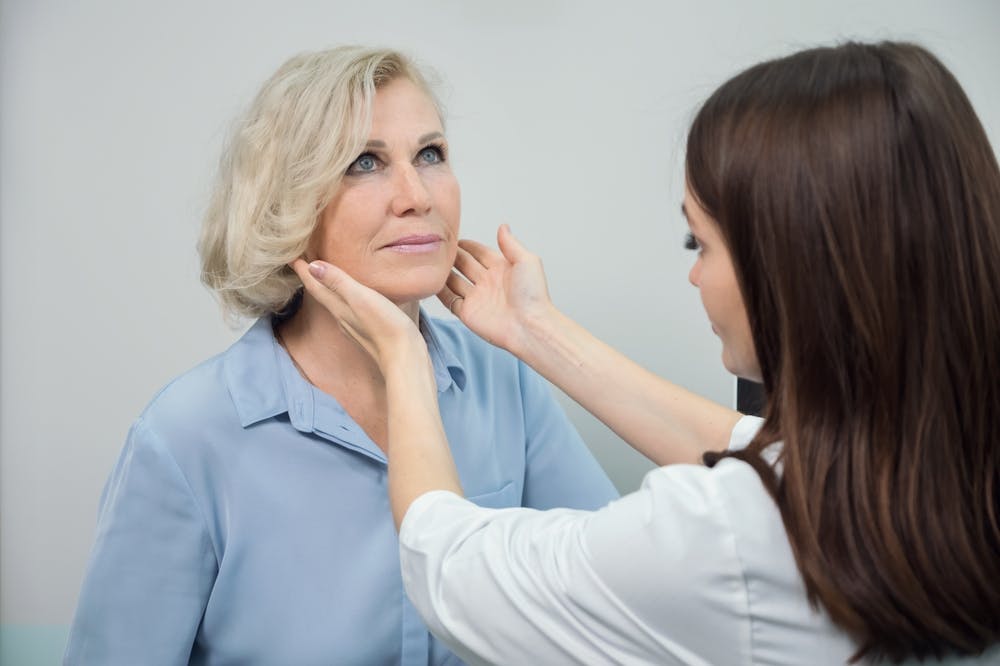 Surgeon assesses patient's neck muscles during a consultation for precise neck lift surgery.