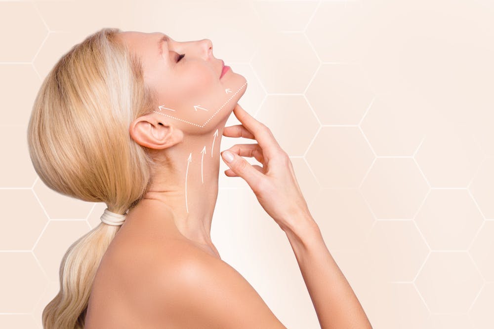 Blonde woman demonstrating the Nefertiti Lift technique for jawline enhancement.