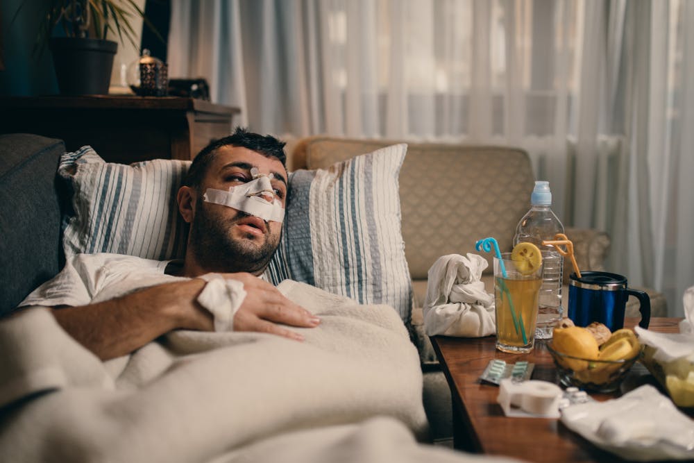 man laying down with bandages on his face after nose surgery