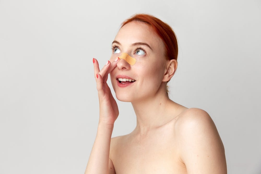 woman with tape on her nose
