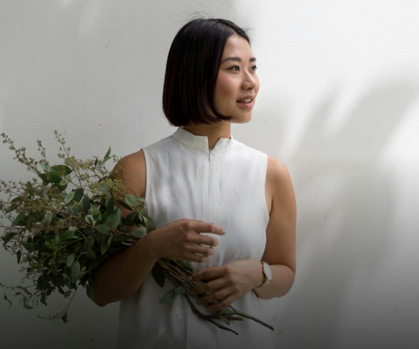 woman with short dark hair carrying flowers