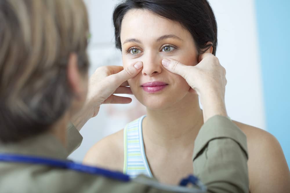 doctor inspecting woman's face before rhinoplasty surgery