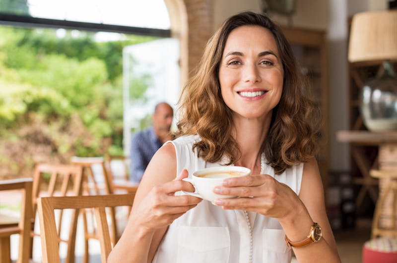 woman smiling and drinking a coffee