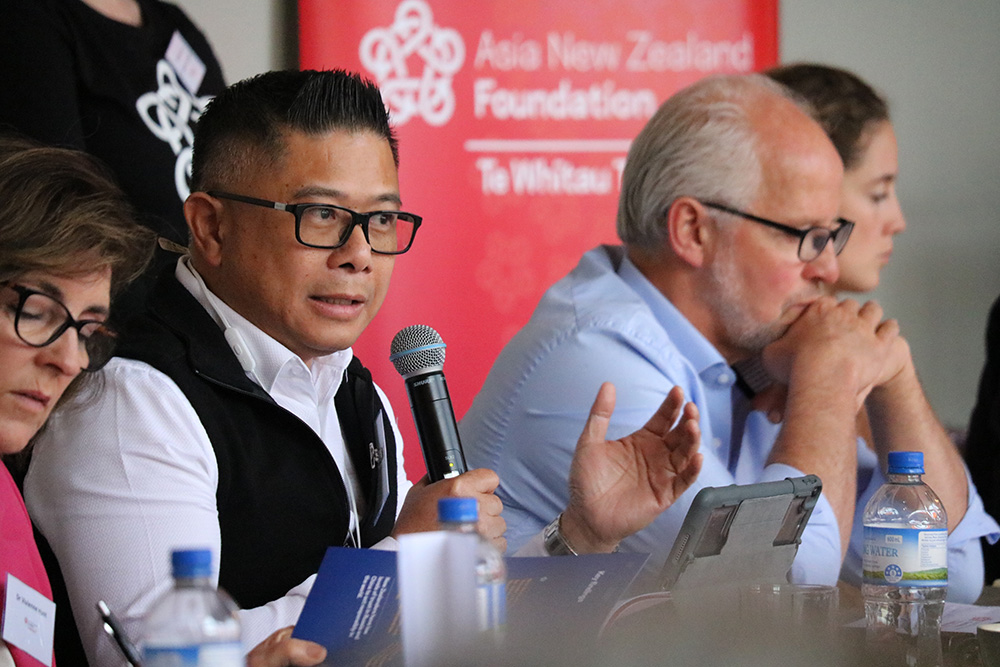 Mitchell Pham speaking into a microphone at a meeting