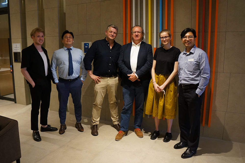 A group of six people including the foundation's executive director Simon Draper posing for a photo against a wall
