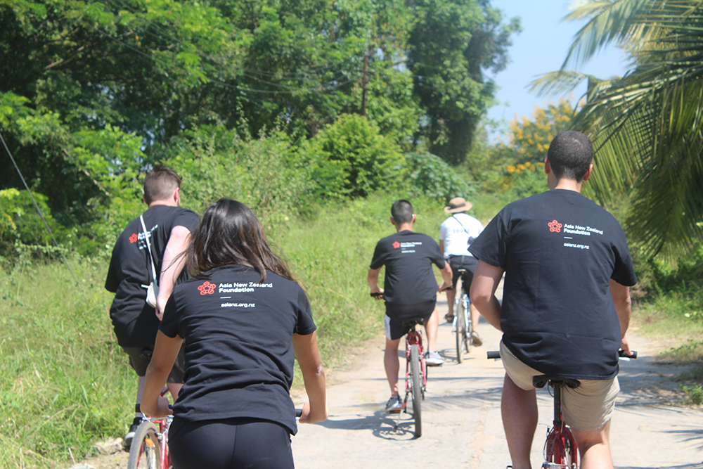 The backs of people riding bikes along a dirt road