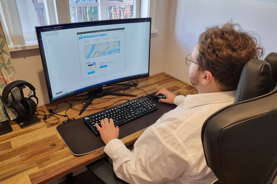 Luke sitting at his computer looking at a rideshare app
