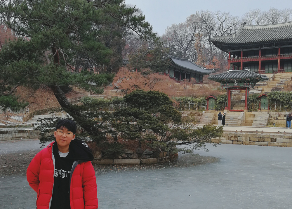 Person in red coat standing in front of traditional building