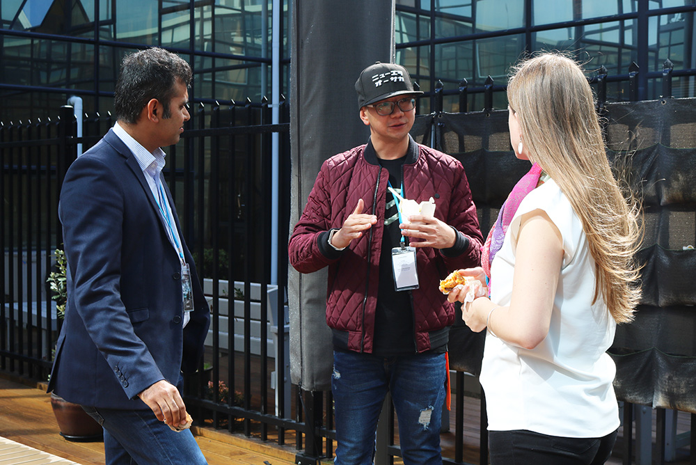 three people chatting outside a mirrored building