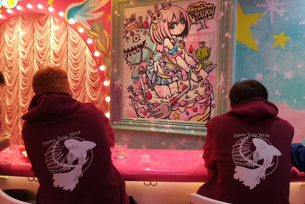 Two boys sitting in a bright pink cafe