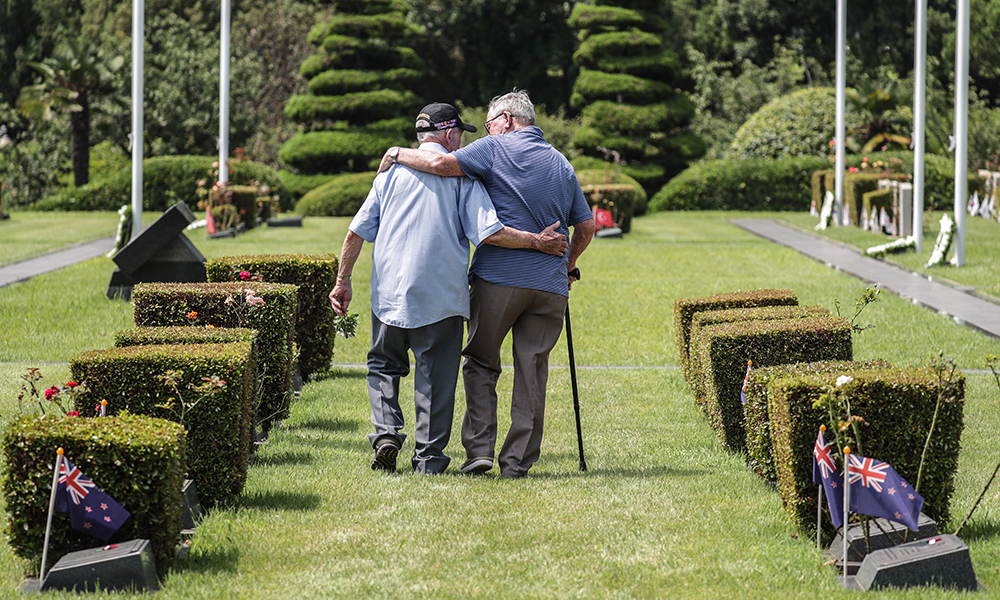 Two New Zealand war veterans arm in arm in a cemetery in Busan