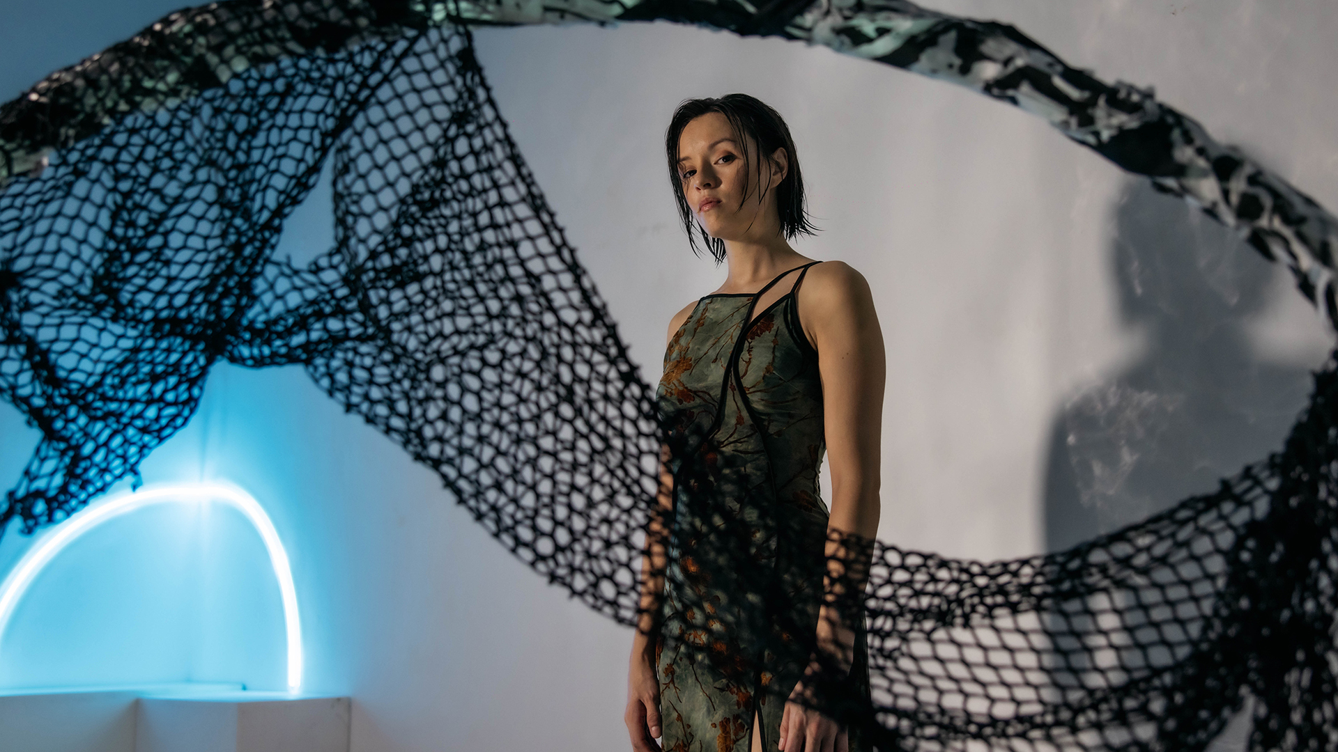 Chye-Ling standing on a set of shadows, lit by neon light
