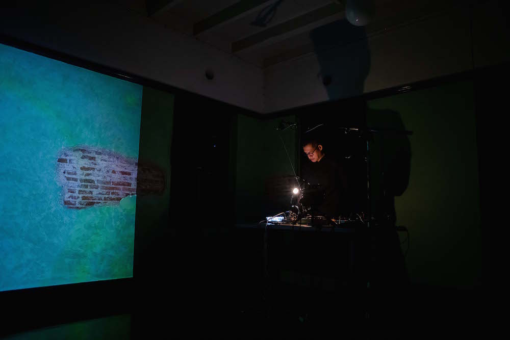 Shayne standing beside a projector projecting images on a wall