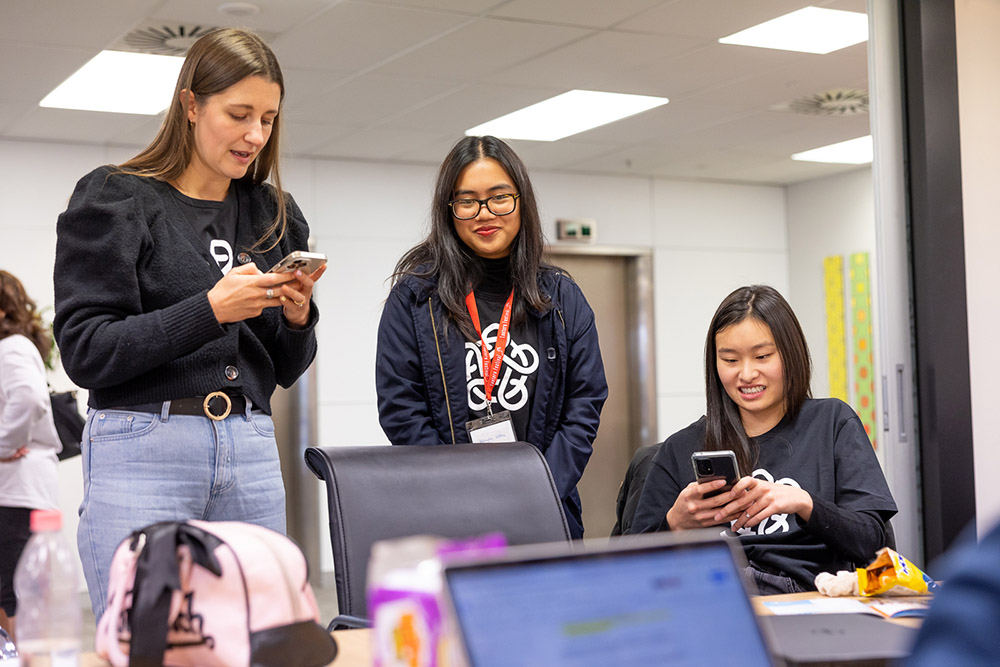 Hannah Duder, Linh Le and Celeste Peh checking their phones