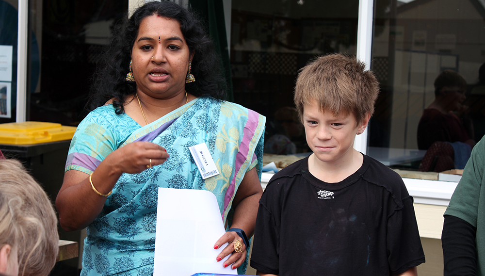 A woman in a sar addressing a group with a boy standing beside her