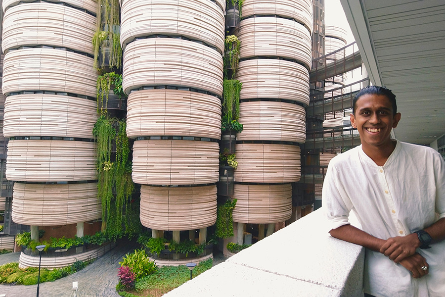 Ajay Ravindran standing in front of a hanging garden in the atrium of a large building