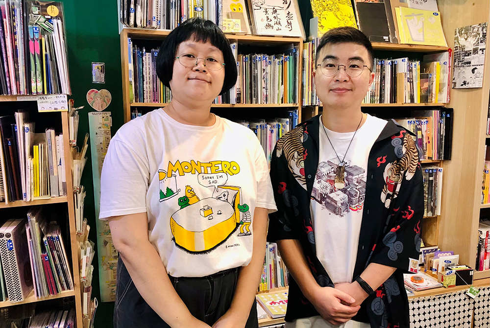 Allan Xia standing beside a woman in front of shelves containing graphic novels and magazines