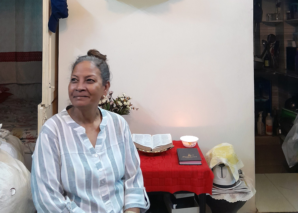 The president of Bow Barracks sitting in a room with a table with a bible on it behind her