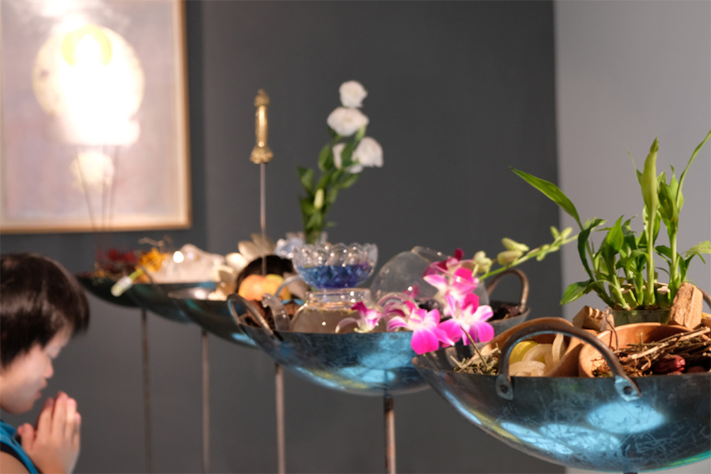 A woman prays in front of the bowls