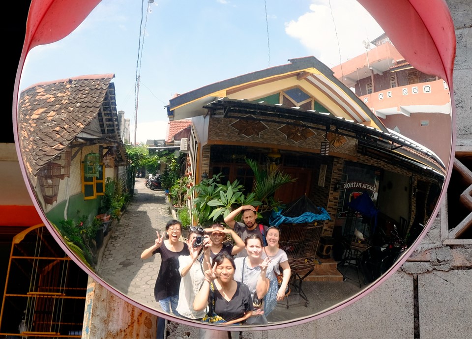 A group of people looking into a mirror used for traffic to see around a corner