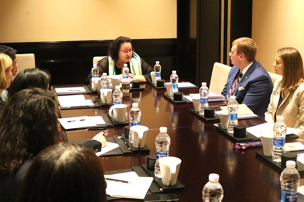 A woman speaking to a group of people at a conference table