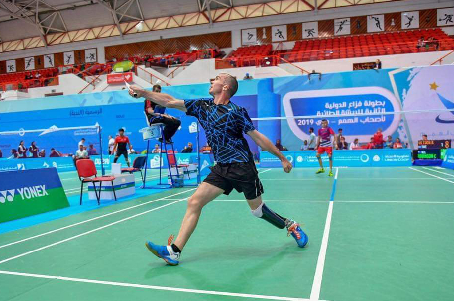 Corrie hitting a shuttlecock during a game in a stadium