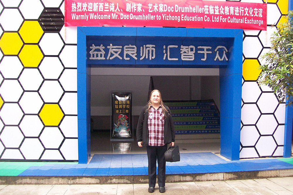 Doc standing outside a building with a banner welcoming him hung across the entrance