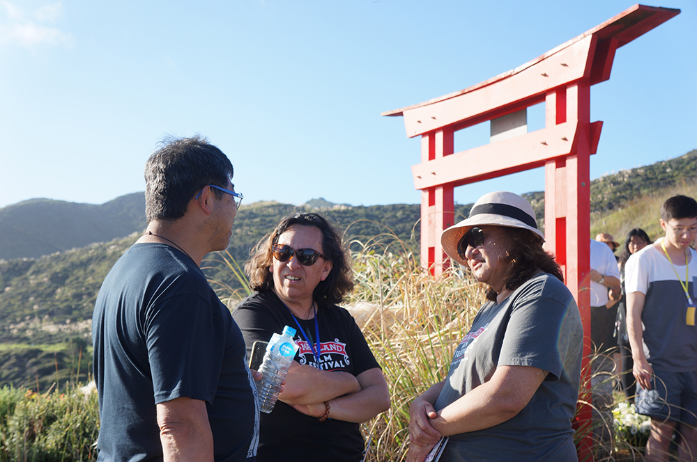 Three people chatting near the Chinese gate erected on the coast near where the Ventnor sank