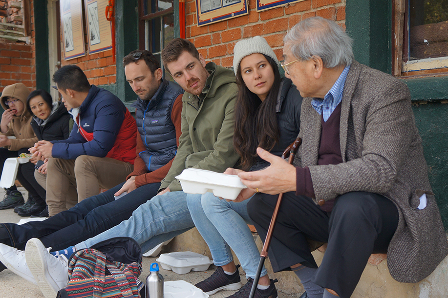 Sebastian sitting on a bench with fellow Leadership Network members listening to a man talk