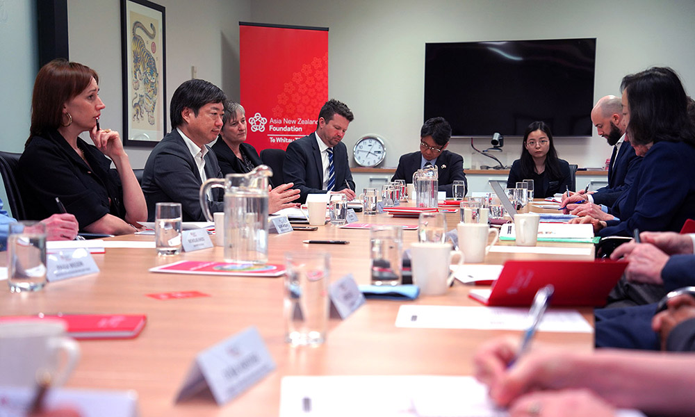 People sitting around a boardroom table taking notes