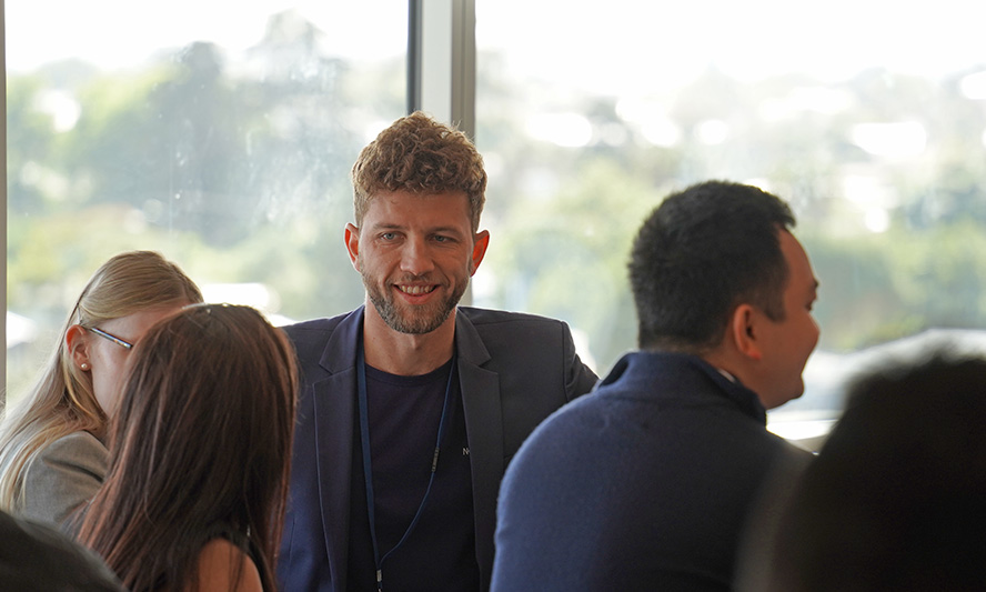 Fenn sitting at a table taking to two women